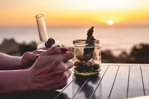 man sitting during sunset with weed pipe